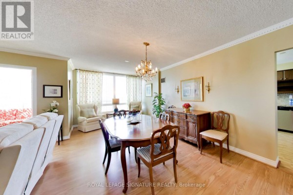 Dining area with a dark wood oval table, chairs, chandelier, and adjacent to a doorway to the kitchen. - 1802 - 1 Clark Avenue W, Vaughan