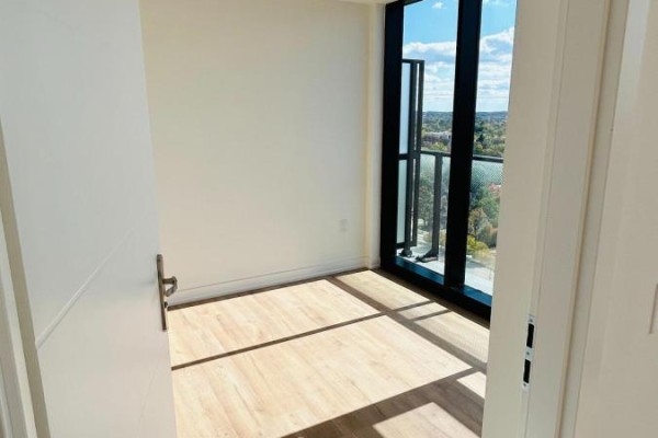 Corner of an empty room with light wood floors and a large window with a balcony. - 1802 - 30 Francis Street S, Kitchener