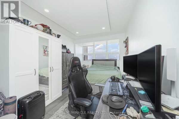 Gaming setup with dual monitors, gaming chair, wardrobe, and bed - 1802 - 8 Lisa Street Brampton