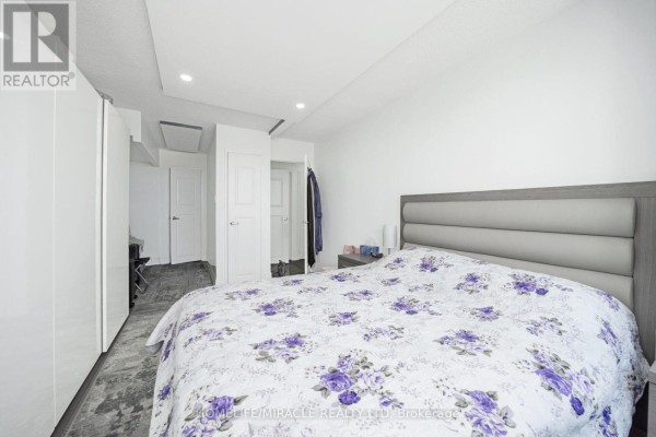 Bedroom with upholstered headboard bed and floral comforter - 1802 - 8 Lisa Street Brampton