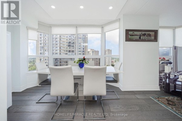 Modern dining room with white table and chairs, bay windows, city view - 1802 - 8 Lisa Street Brampton