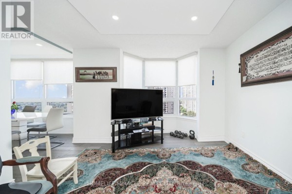 Living room with bay window, TV, area rug, and dining table - 1802 - 8 Lisa Street Brampton