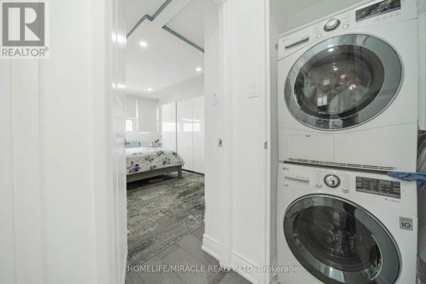Stacked LG washer/dryer & bedroom view with modern white cabinets and rug - 1802 - 8 Lisa Street Brampton