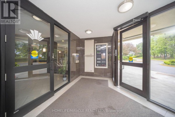 Building entrance with glass doors, call box, and electrical panels - 1802 - 8 Lisa Street Brampton