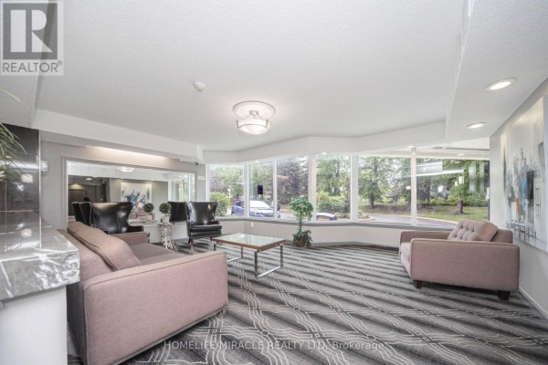 Living room with bay window, sofa, armchairs, and wall art - 1802 - 8 Lisa Street Brampton