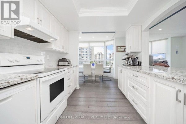 Renovated kitchen with white cabinets, granite countertops, and breakfast nook - 1802 - 8 Lisa Street Brampton