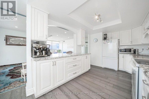 White kitchen with espresso machine, granite counters, and grey wood floors - 8 Lisa Street Brampton
