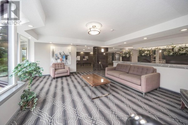 Building lobby with sofa, armchair, coffee table, artwork, and patterned carpet - 1802 - 8 Lisa Street Brampton