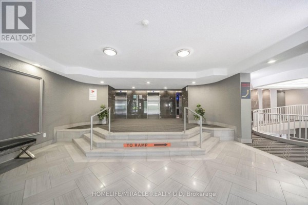 Elevators, ramp sign, and curved staircase in a modern building hallway - 1802 - 8 Lisa Street Brampton