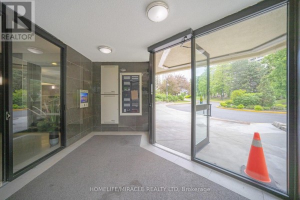 Building entrance with glass doors, intercom, and exterior view - 8 Lisa Street Brampton