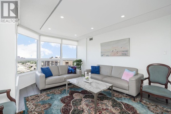 Living room with gray sofas, marble coffee table, ornate rug, and large windows - 1802 - 8 Lisa Street Brampton