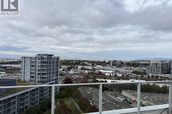 View from balcony overlooking buildings, water, and distant mountains under cloudy sky. - 1802 3333 Brown Road, Richmond