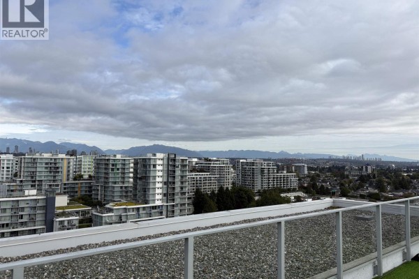 Rooftop view of city skyline with mountains in the distance and glass railings. - 1802 3333 Brown Road, Richmond