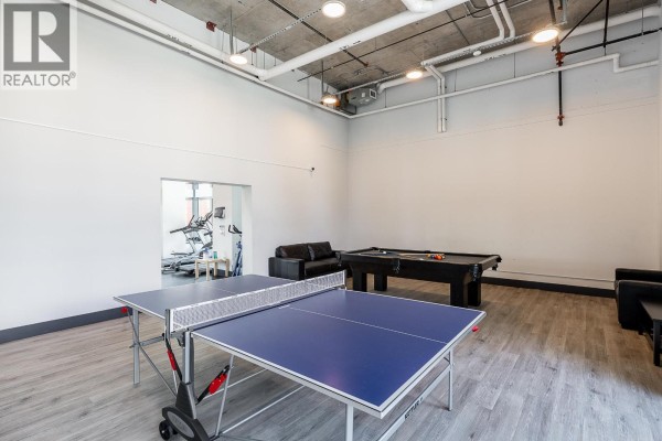 Lobby area with marble wall, tile flooring, and two black chairs. - 1803 518 Whiting Way, Coquitlam