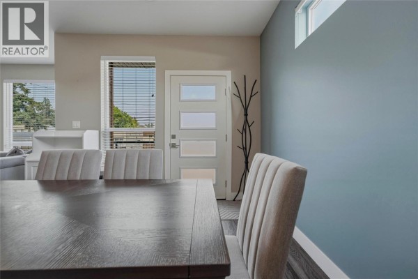 Dining area with a dark wood table, upholstered chairs, and a glass-paned front door. - 1804 46 Avenue Unit# 2, Vernon