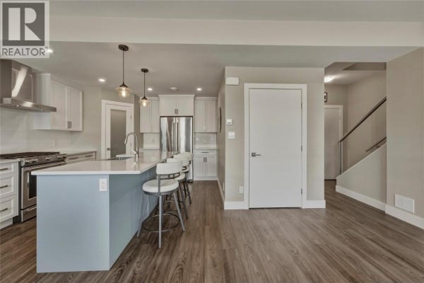 View of the kitchen with a light blue island, white cabinetry, and stainless steel appliances. - 1804 46 Avenue Unit# 2, Vernon
