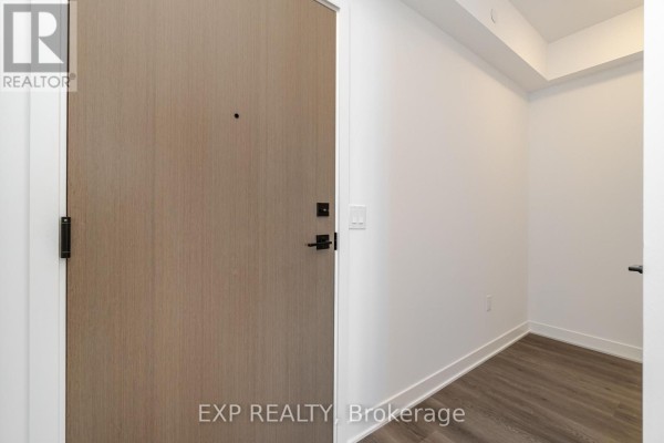 Apartment entrance with light wood door, black hardware, and neutral walls. - 1805 - 36 Zorra Street, Toronto