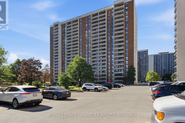 Exterior view of the apartment building with a large parking lot filled with cars. - 1805 - 4 Kings Cross Road, Brampton