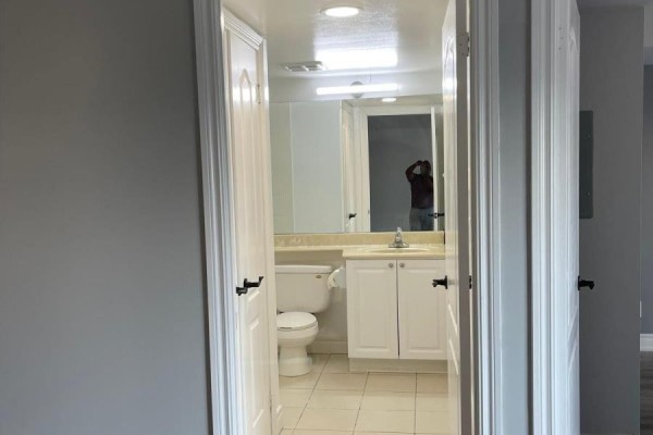 Apartment bathroom with white toilet, white vanity, and tiled floor, viewed from hallway. - 1805 - 70 Town Centre Court, Toronto