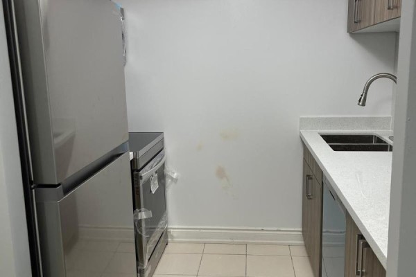 Apartment kitchen with stainless steel refrigerator, oven, and sink with grey cabinets. - 1805 - 70 Town Centre Court, Toronto