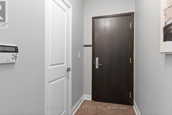 Interior view of a condo hallway with a dark wood front door and white door. - 1805 - 80 Absolute Avenue S, Mississauga