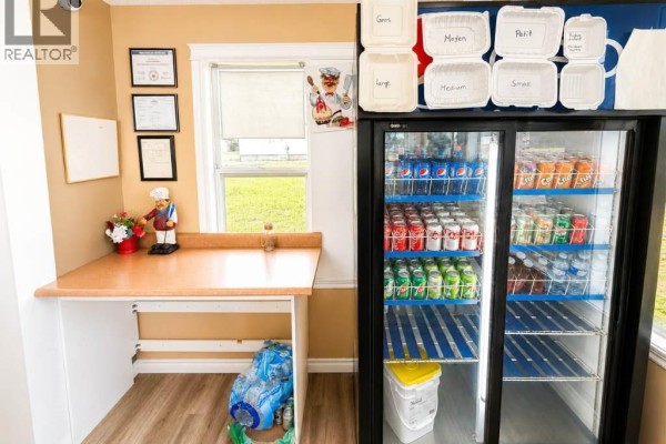 Close-up interior view of a beverage cooler filled with drinks next to a counter and window. - 1805 Route 322, Robertville