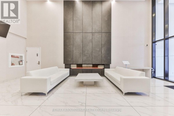Lobby area featuring two white sofas, a coffee table, and a large feature wall in grey. - 1806 - 15 Queen Street, Hamilton