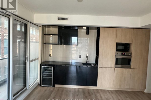 Modern kitchen with light wood cabinets, black countertops, and stainless steel appliances. - 1806 - 70 Temperance Street, Toronto