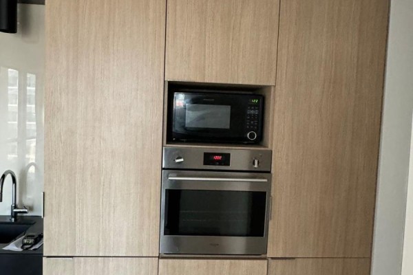 Close-up of built-in microwave and oven with light wood cabinetry. - 1806 - 70 Temperance Street, Toronto
