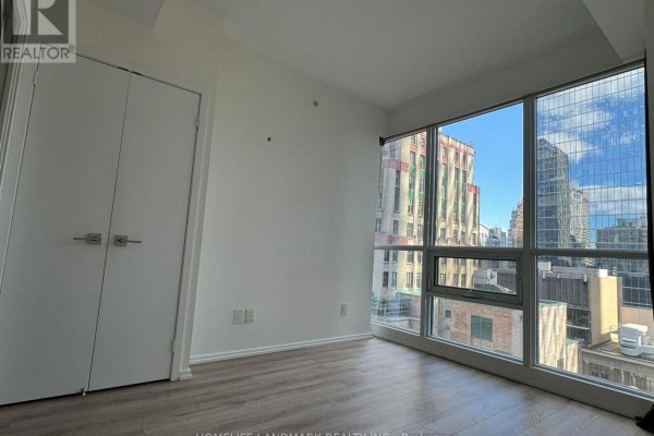 Bedroom with double closet doors and large corner windows with city views. - 1806 - 70 Temperance Street, Toronto