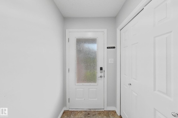 Interior front entry with white door, frosted glass panel, and dark brown door hardware. - 1806 28 St Nw Nw, Edmonton