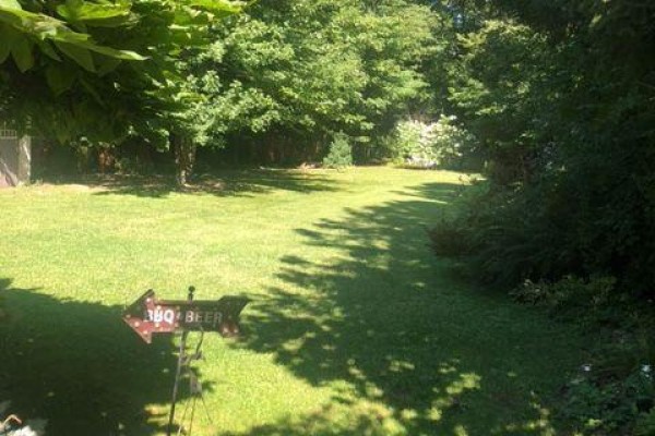 Spacious green backyard with mature trees, shadows, and a directional sign. - 1806 Parkhurst Avenue, London East
