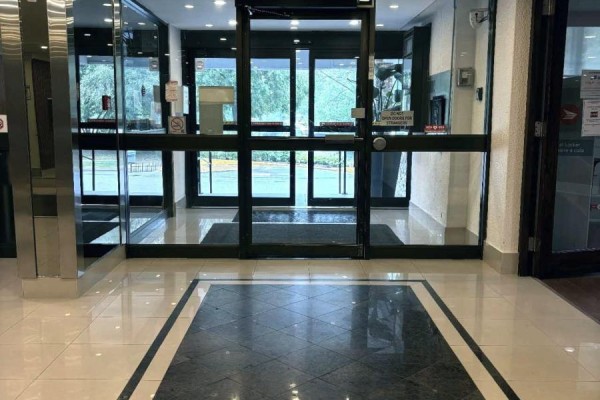 Glass double doors lead into the apartment building's lobby with black mats on the floor. - 1807 - 85 Emmett Avenue, Toronto