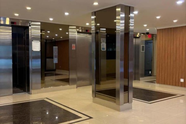 The apartment building's lobby features stainless steel elevators and mirrored walls with wood paneling. - 1807 - 85 Emmett Avenue, Toronto