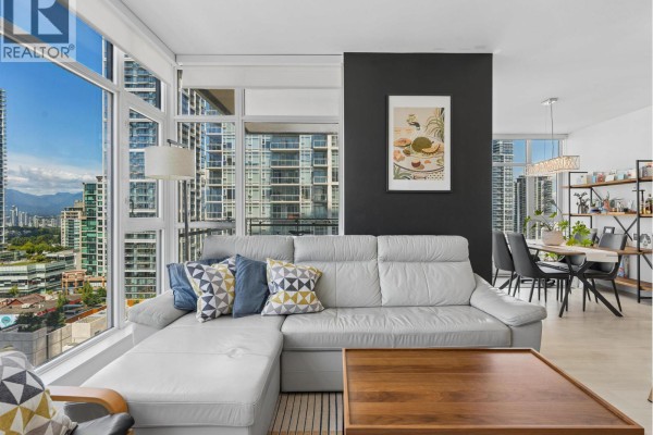 Living room with a white sectional sofa, coffee table, and expansive city views. - 1807 6098 Station Street, Burnaby