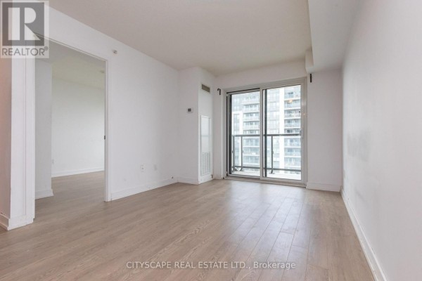 Living area with natural light from a large balcony door and view of city buildings. - 1808 - 1410 Dupont Street, Toronto