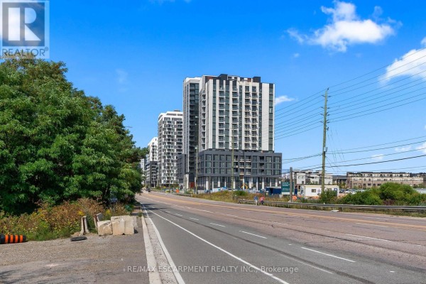 Exterior view of modern high-rise apartment buildings on a suburban street with trees and utility poles. - 1808 - 3079 Trafalgar Road, Oakville