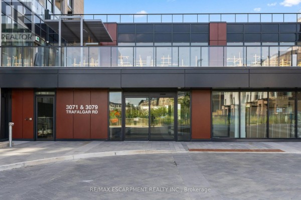 Ground-level entrance to the apartment buildings at 3071 & 3079 Trafalgar Road with glass doors and dark paneling. - 1808 - 3079 Trafalgar Road, Oakville