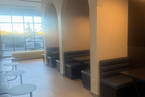 Seating area with view of exterior trees and cars through large windows. - 1809 - 225 Malta Avenue, Brampton