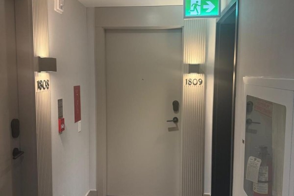 Apartment hallway with beige door marked 1809, flanked by ribbed wall panels and sconces. - 1809 - 225 Malta Avenue, Brampton