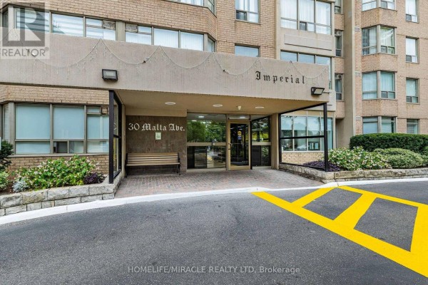 Building entrance with a covered walkway, bench, and glass doors. - 1809 - 30 Malta Avenue, Brampton