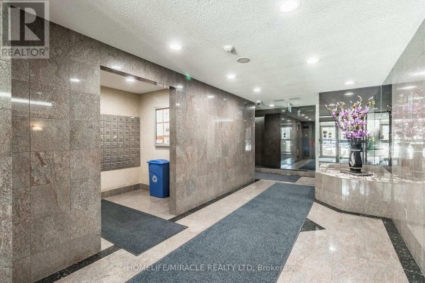 Building lobby with marble walls, mailboxes, a blue trash bin, and carpet runners. - 1809 - 30 Malta Avenue, Brampton