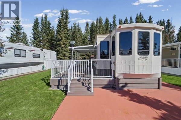 Mobile home exterior showing deck, ramp, and surrounding trees. - 181, 32379 Range Road 55, Rural Mountain View County