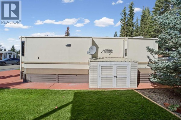 Rear exterior of mobile home showing storage shed and trees. - 181, 32379 Range Road 55, Rural Mountain View County