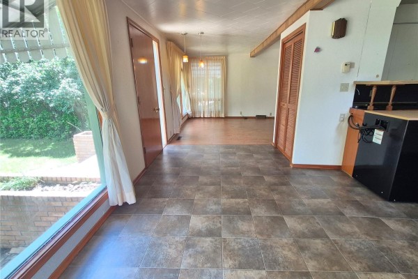 Interior view of a sunroom with tile flooring, large windows, and access to the outdoors. - 181 2nd Street W, Bengough