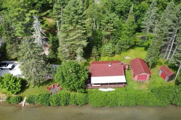 Drone shot of a lakeside cottage, garage, small shed, and surrounding forest. - 181 Ch. Du Petit-cayamant, Cayamant