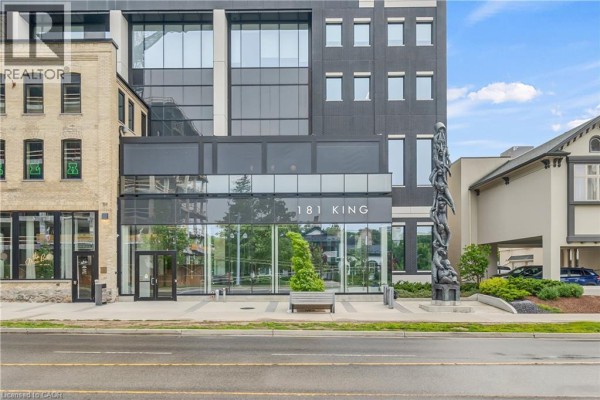 Close-up of the building's entrance at 181 King Street, featuring glass doors and a large sculpture. - 181 King Street S Unit# 1408, Waterloo