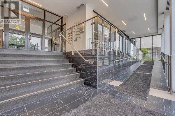 Interior view of the building lobby showing a marbled floor, metal railings, and a ramp. - 181 King Street S Unit# 1408, Waterloo