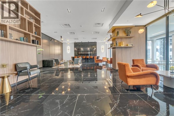 Luxurious lobby seating area with marble floors, orange velvet armchairs, and a long bar. - 181 King Street S Unit# 1408, Waterloo