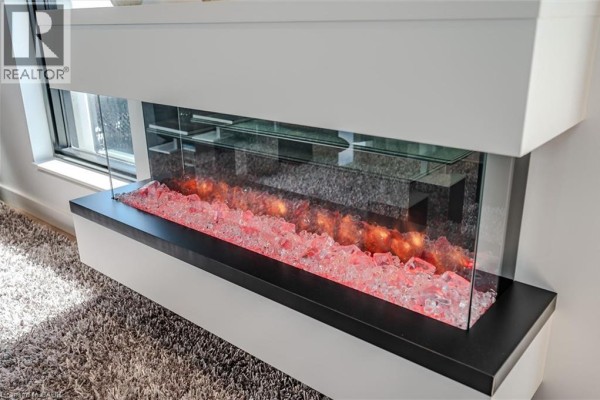 Close-up of a modern electric fireplace with colorful glass rocks. - 181 King Street S Unit# 1714, Waterloo